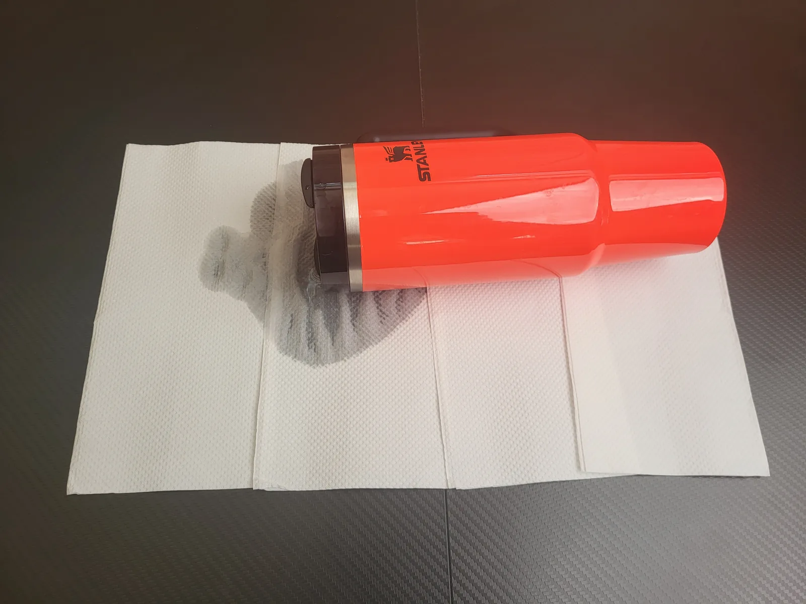 A red water bottle inverted on paper towels during a leak test.