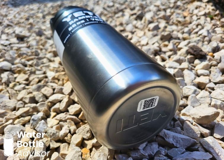 YETI Rambler 26 oz bottle lying on gravel, showing its durable stainless steel body