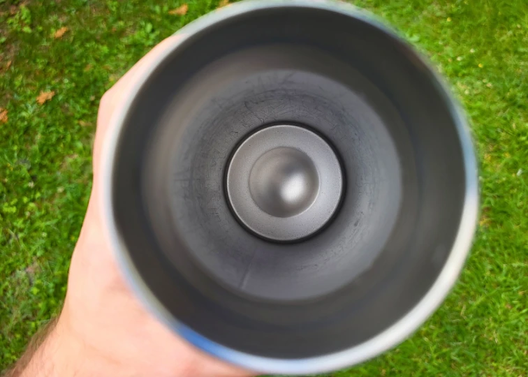 Interior view of a Hydro Flask bottle, showing the stainless steel bottom with a circular indentation against a grassy background.