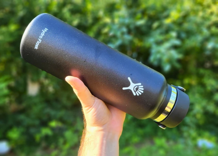 A black Hydro Flask water bottle tilted downwards, demonstrating its leak-proof seal.