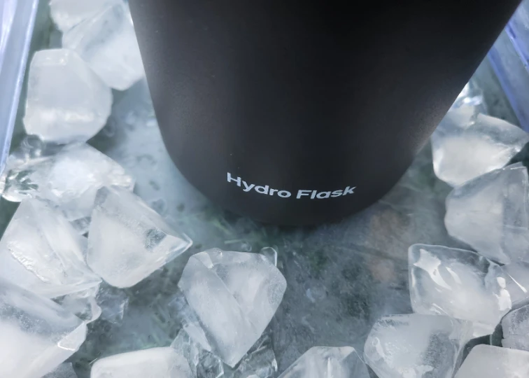 A Hydro Flask water bottle surrounded by ice cubes, demonstrating its insulation quality.