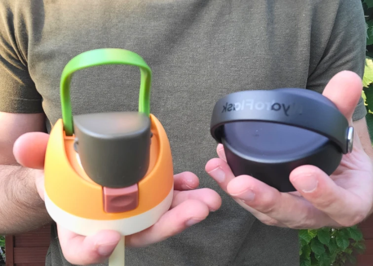 Two water bottle lids are held side by side; the left is an Owala FreeSip, and the right is a Hydro Flask.