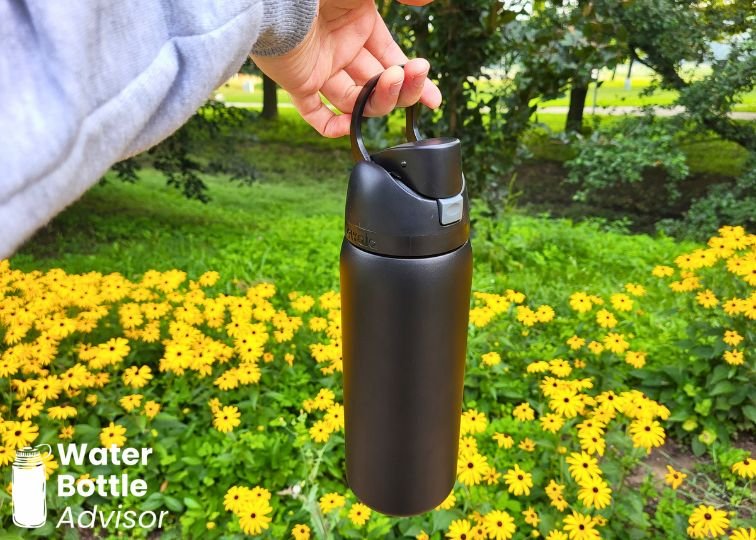 Owala FreeSip 32 oz bottle being carried by its built-in handle outdoors