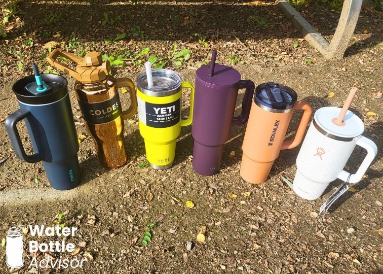 Tumblers from Owala, Coldest, YETI, Simple Modern, Stanley, and Hydro Flask lined up outdoors for comparison