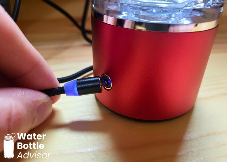 Close-up of the EVOLV hydrogen water bottle magnetic charger connecting to the charging port on the red base