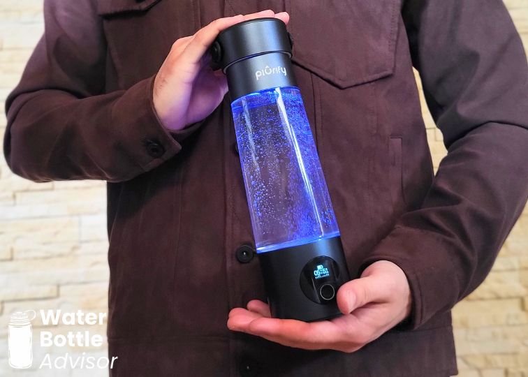 Jeremiah Kowalski holding the Piurify Hydrogenator hydrogen water bottle while it glows blue and produces hydrogen bubbles