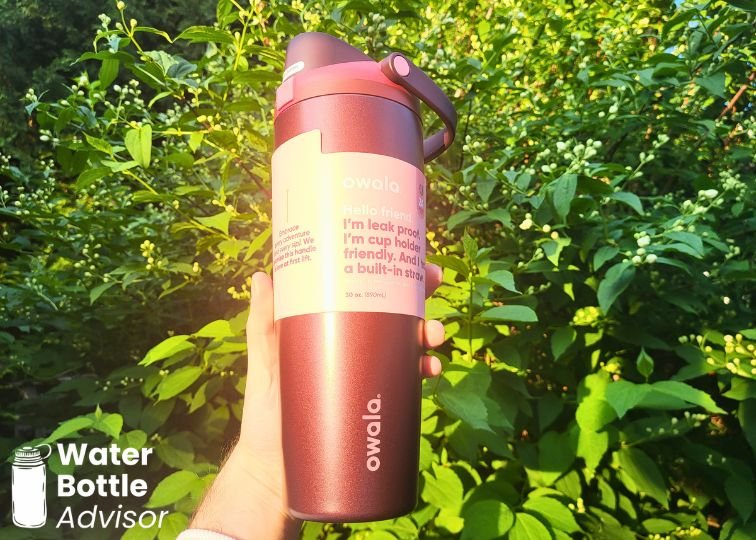 Owala FreeSip Sway 30 oz burgundy bottle being held outdoors in bright sunlight