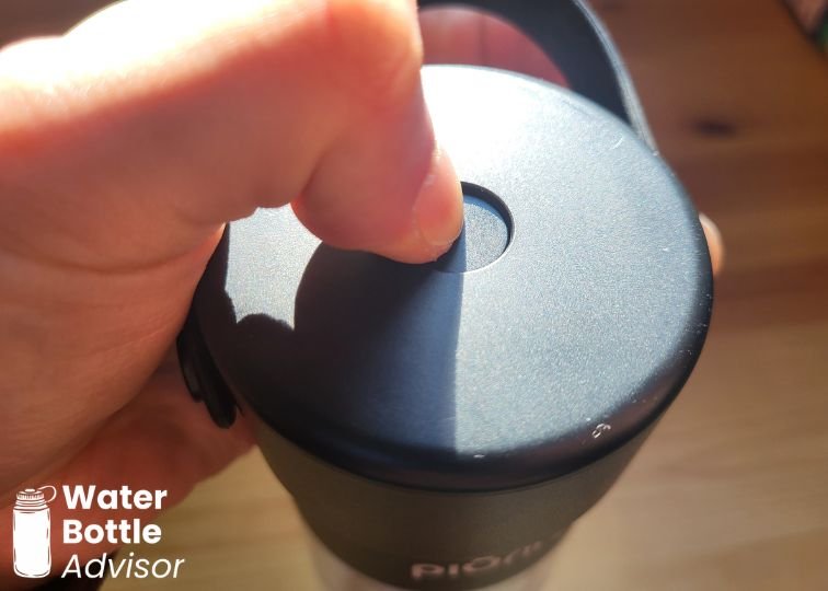 Close-up of the Piurify Hydrogenator hydrogen water bottle lid showing the pressure release button being pressed