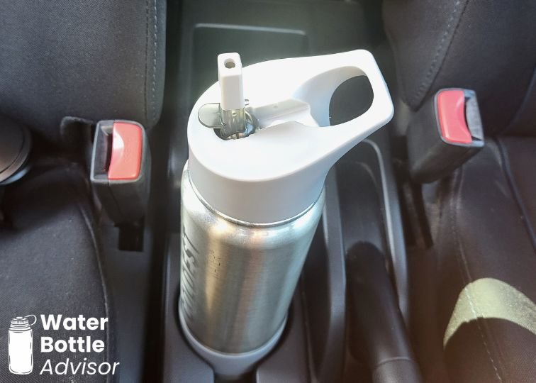 Coldest 24 oz stainless steel water bottle sitting in a car cup holder with a straw lid