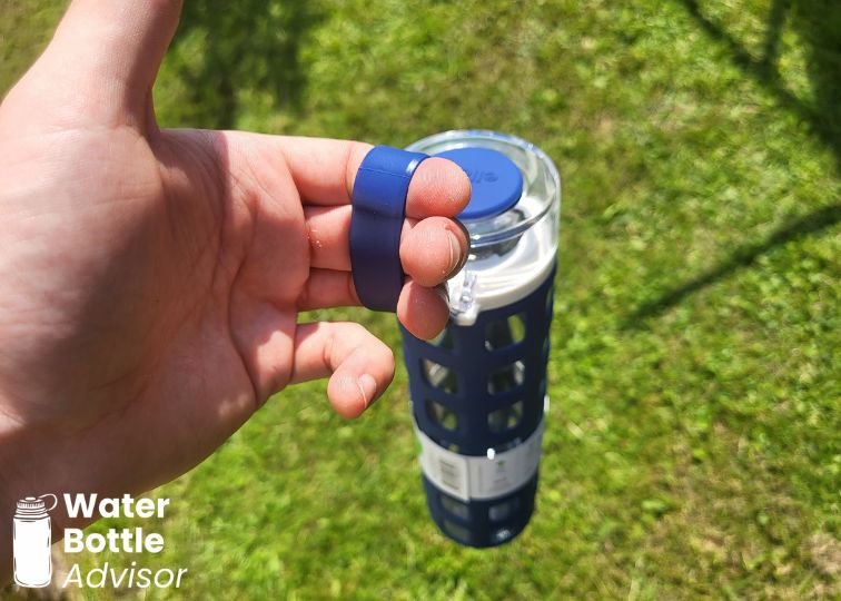 Close-up of the Ello Syndicate glass water bottle carry loop being held outdoors