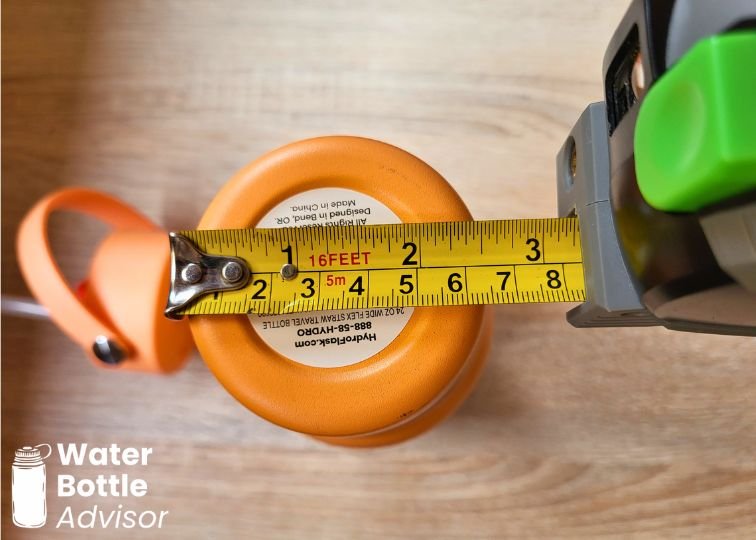 Hydro Flask 24 oz orange travel bottle measured with a tape measure across the base