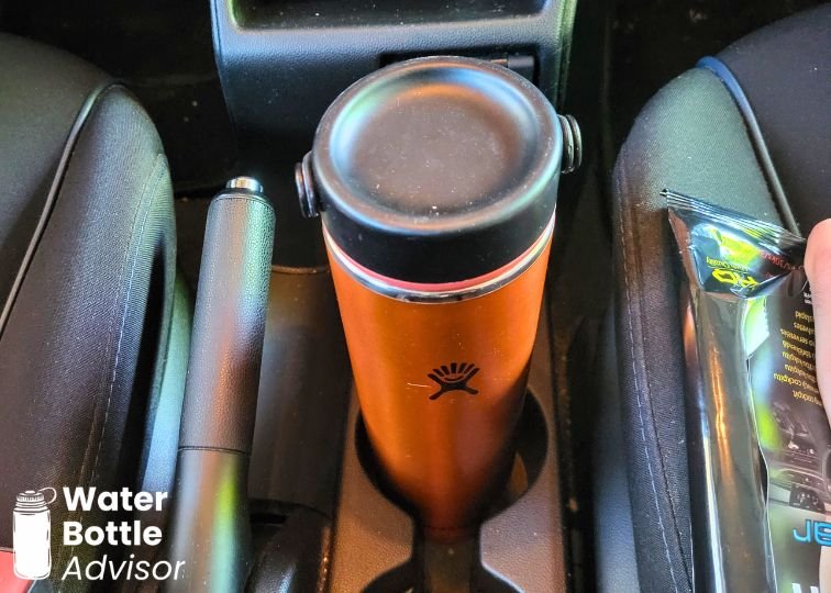 Hydro Flask Trail Series Lightweight 24 oz orange water bottle sitting in a car cup holder
