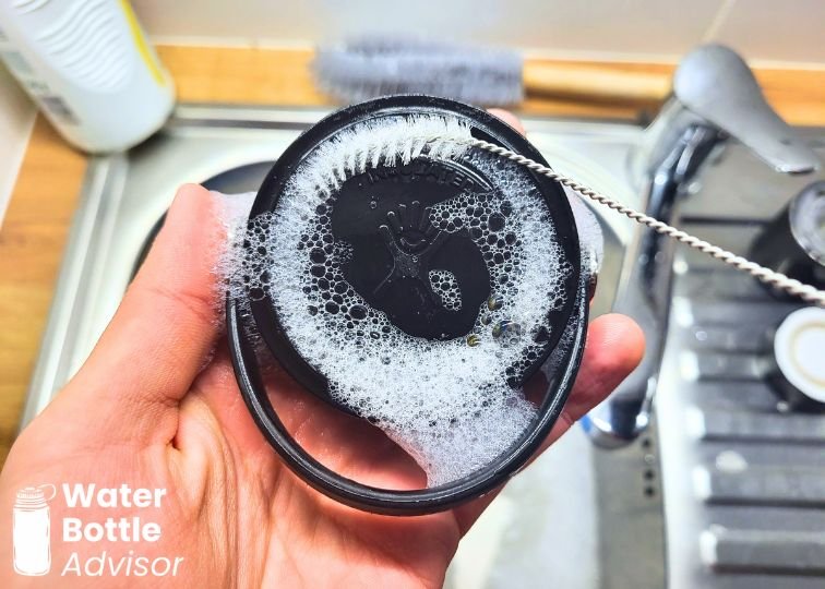 Hydro Flask Wide Mouth Flex Cap being cleaned with a straw brush and soapy water