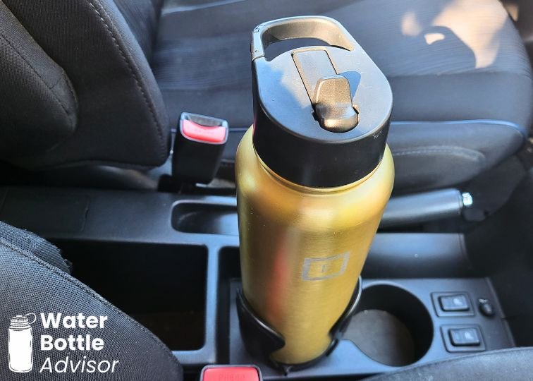 Iron Flask 40 oz bottle sitting in an adjustable car cup holder between the front seats