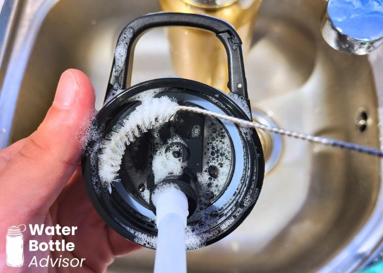 Iron Flask 40 oz straw lid being cleaned with a straw brush and soapy water