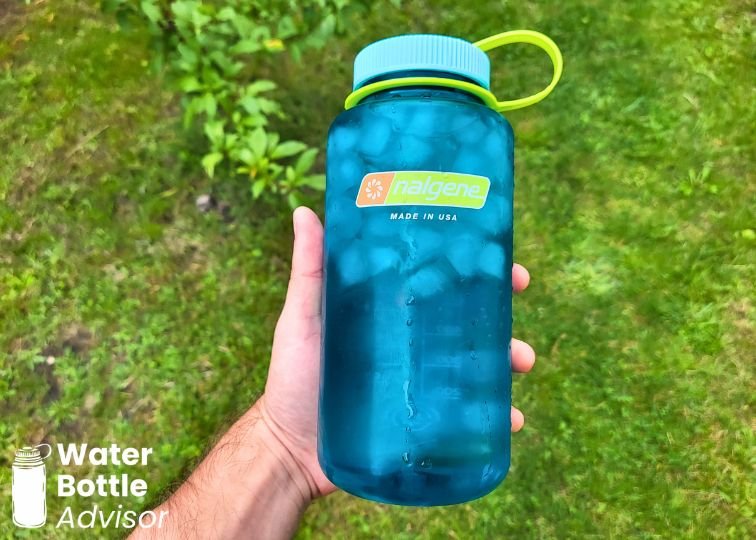 Nalgene wide-mouth 32 oz blue plastic water bottle filled with ice and held outdoors