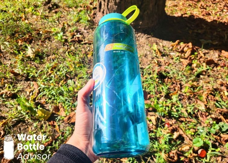 Nalgene wide-mouth 40 oz blue plastic water bottle being held outdoors in a wooded area