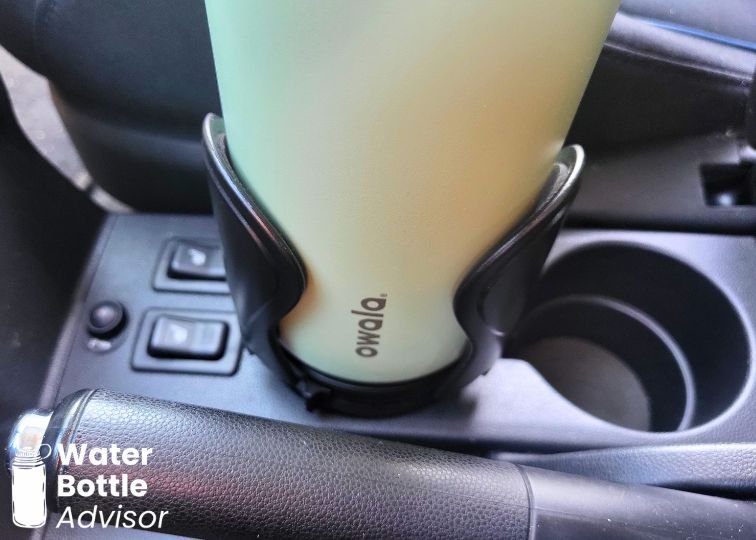 Owala FreeSip 40 oz bottle sitting in an adjustable car cup holder between the front seats