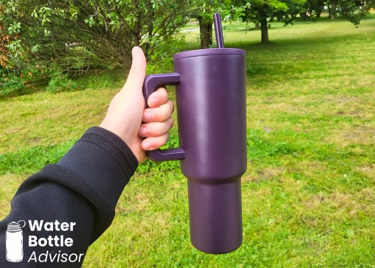 Simple Modern Trek Tumbler 40 oz being held by the handle outdoors
