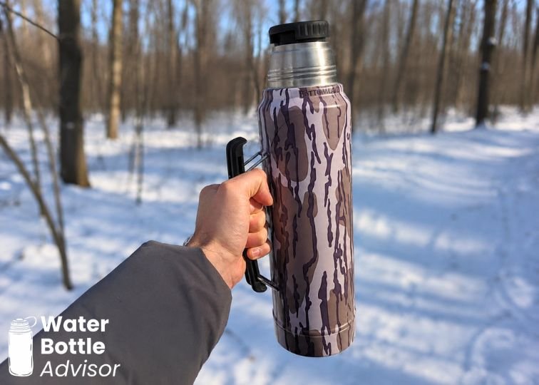 Stanley Classic Legendary Bottle 1.1 QT being carried by its handle in a snowy forest