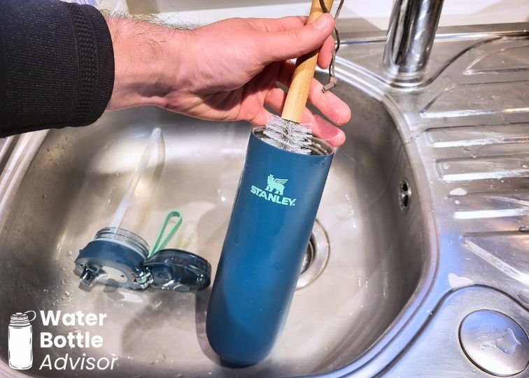 Stanley FlowState Spring Bottle 20 oz being cleaned with a brush under running water in a sink