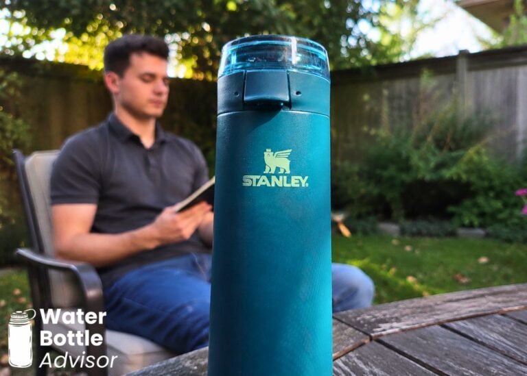Stanley FlowState Spring Bottle 20 oz standing on an outdoor table with a person blurred in the background