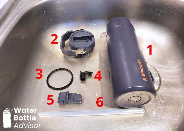 Stanley IceFlow 24 oz bottle disassembled into six parts for cleaning in a sink