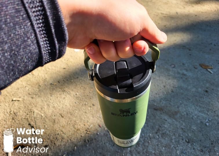 Stanley IceFlow 30 oz tumbler being carried by its lid handle outdoors