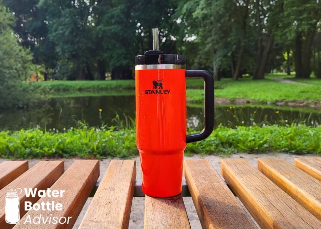 Stanley Quencher H2.0 FlowState 30 oz tumbler standing on a park bench near a pond