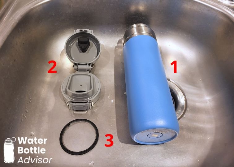 Stanley Quick-Flip Go 24 oz bottle disassembled into three parts for cleaning in a sink