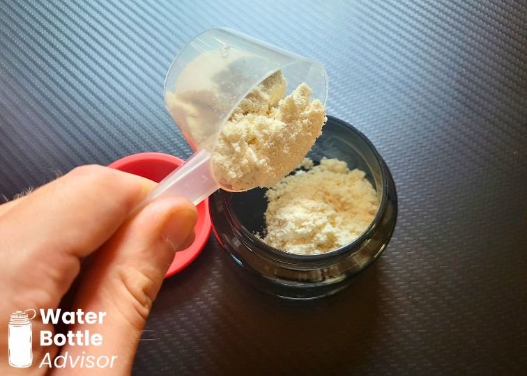 Protein powder being poured into the Stanley Vitalize Shaker Bottle bottom storage container