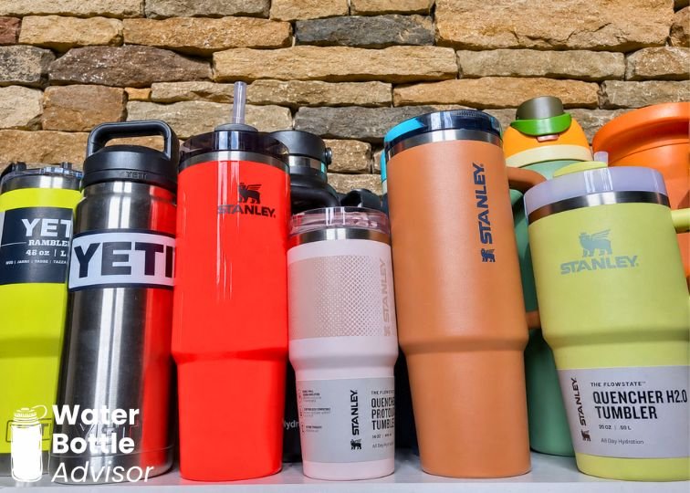 Stanley and YETI reusable water bottles and tumblers lined up outdoors for comparison