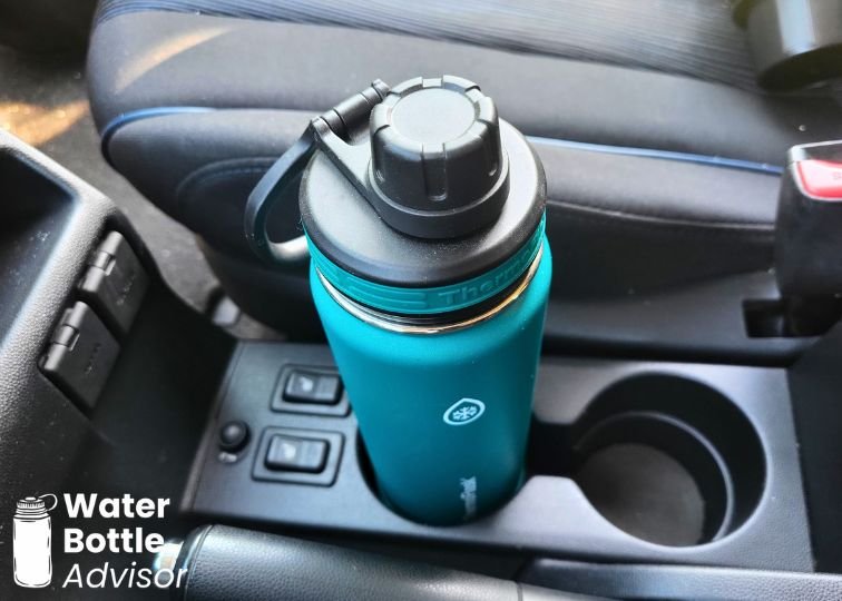 ThermoFlask 24 oz bottle sitting in a car cup holder between the front seats