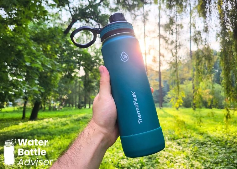 ThermoFlask 24 oz bottle being held outdoors in a grassy park