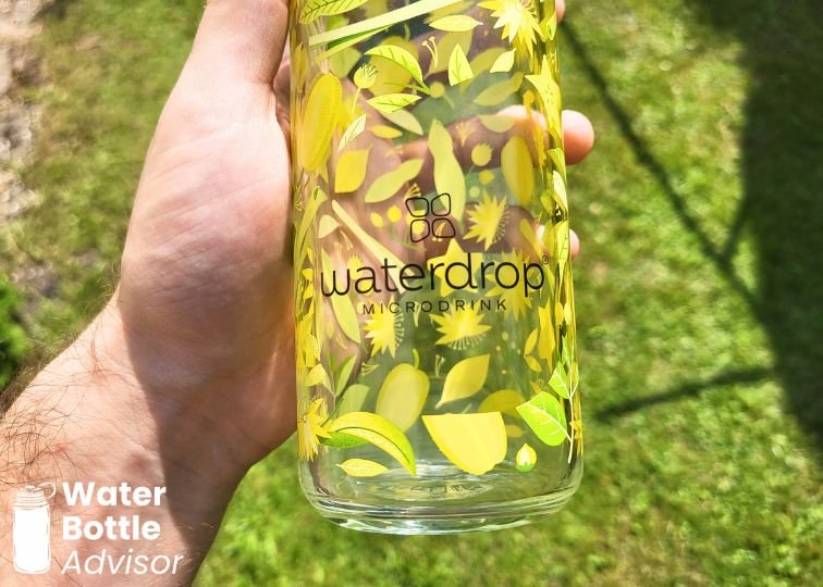 Waterdrop Microdrink glass water bottle with green floral design being held outdoors