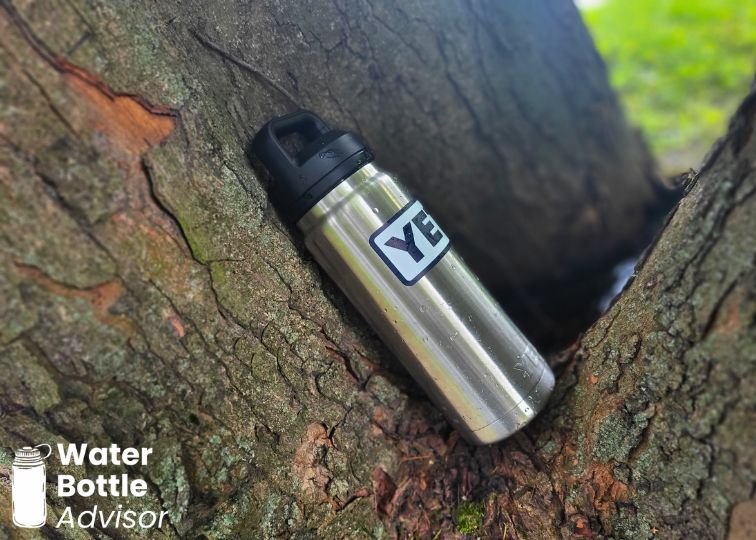 YETI Rambler 26 oz stainless steel water bottle resting against a tree trunk outdoors