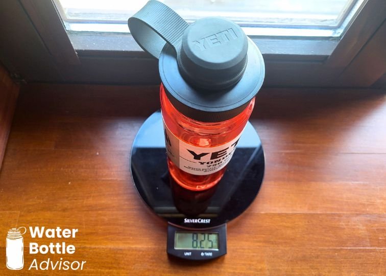 YETI Yonder 25 oz red plastic water bottle being weighed on a digital kitchen scale